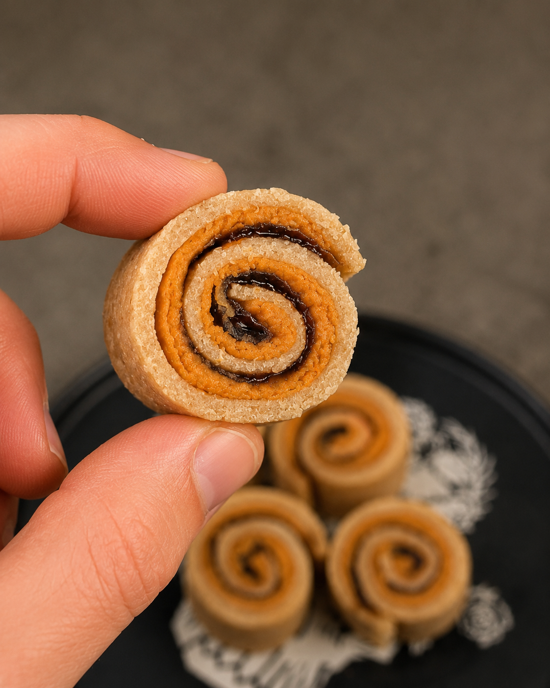 A bite-sized SuperRolls PB&J roll-up held between fingers